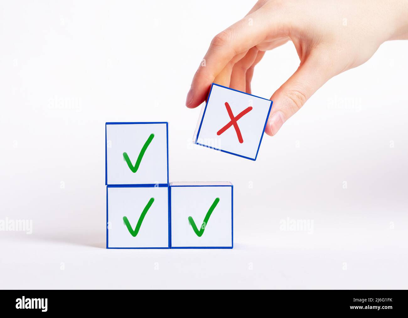 Hand choosing cube with cross instead of blocks with check mark. Negative decision, rejection choice, wrong answer concept. High quality photo Stock Photo