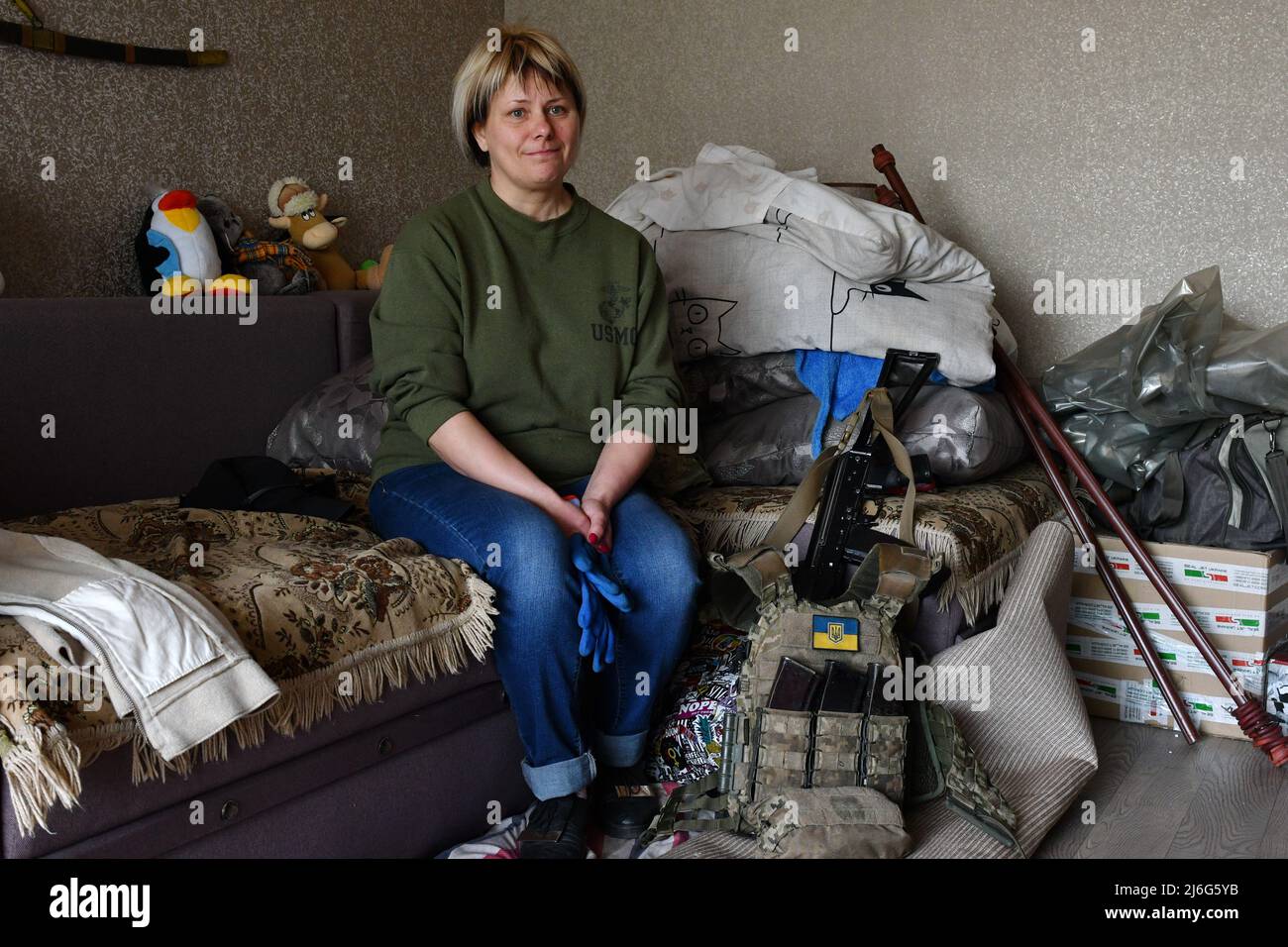Elena, 46 year old seated next to her son's ammunition and weapon, waits for her son, a Ukrainian army soldier to help him clean his flat after his apartment building was damaged by Russian shelling in Dobropillya. Russia has been forced to move 'depleted and disparate' forces to eastern Ukraine, according to the latest intelligence report from the U.K. Defense Ministry on Saturday. The U.K. said that 'many of these units are likely suffering from weakened morale.' Stock Photo