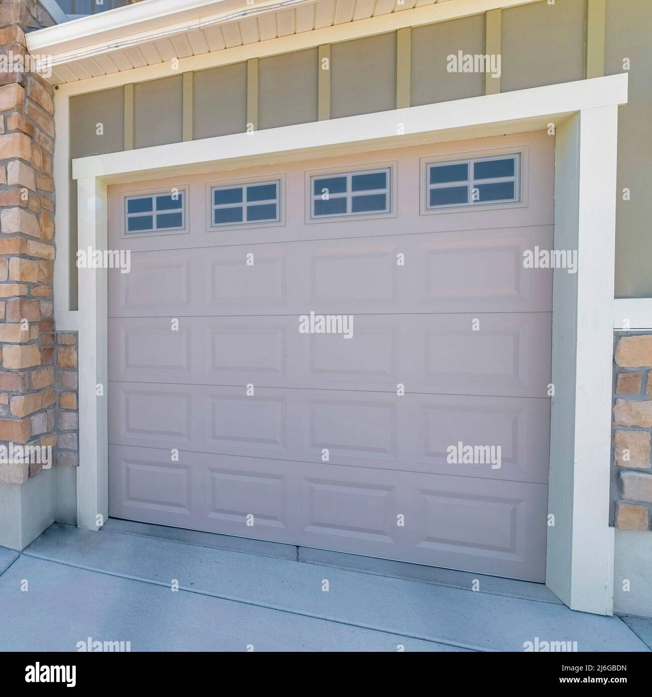 Square Three car garage exterior with stone veneer and green board and