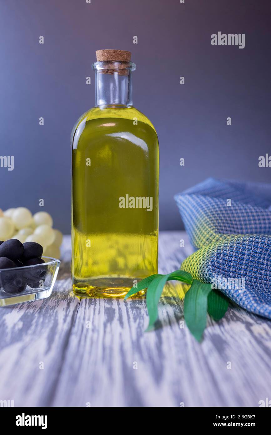 olive oil in a glass bottle with black olives and grapes Stock Photo