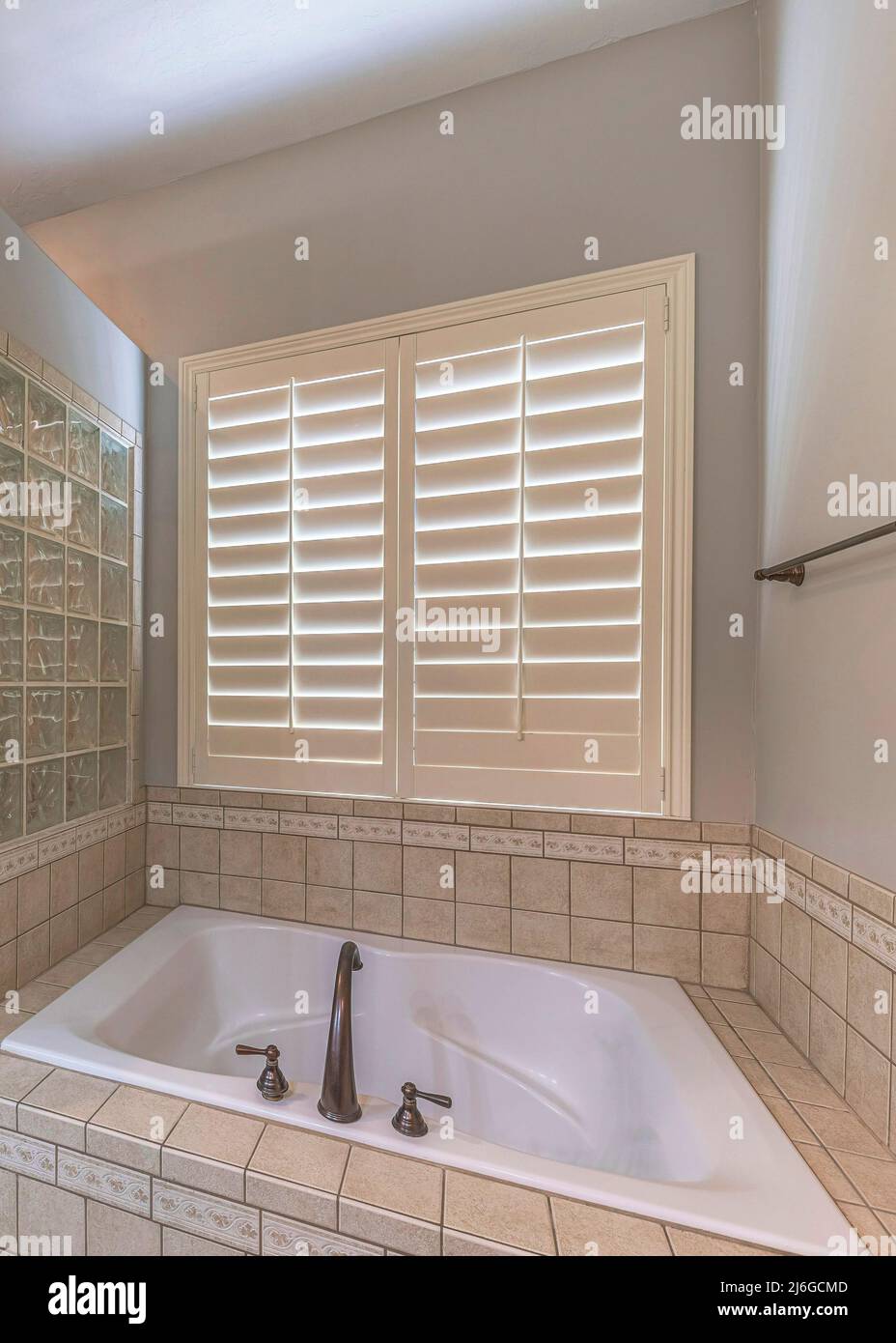 Vertical Bathtub with ceramic tiles surround and glass blocks wall