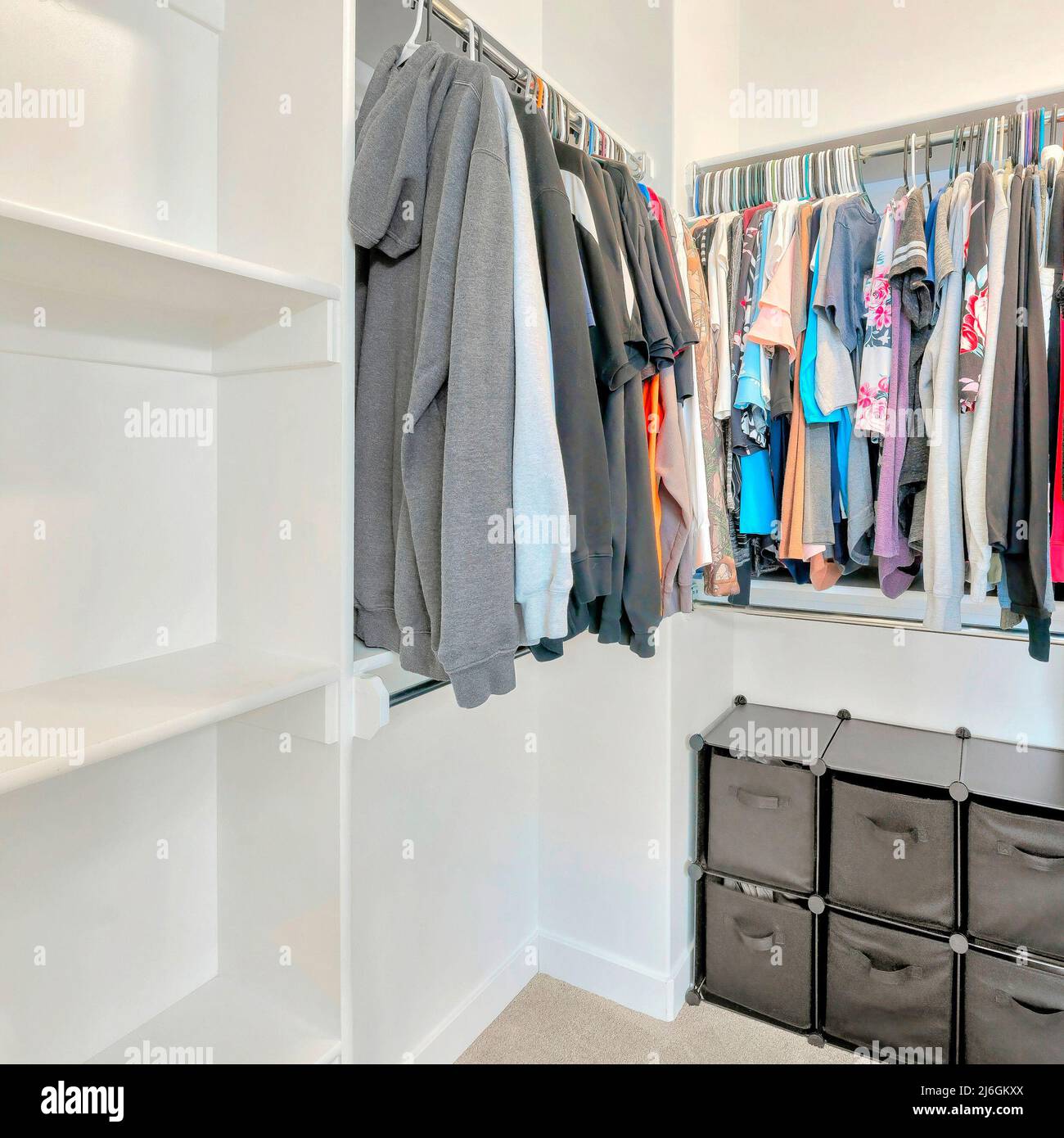 Square Small walkin closet with hanging sweaters, shirts and blouse on