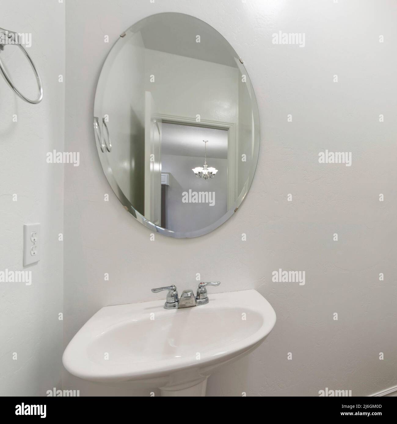 Square White powder room interior with toilet and sink with oval mirror ...