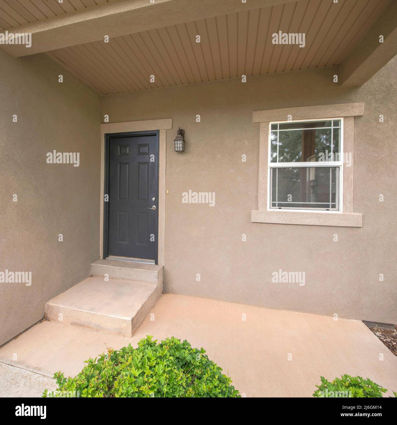 Square Entrance of a house with black front door and concrete doorsteps