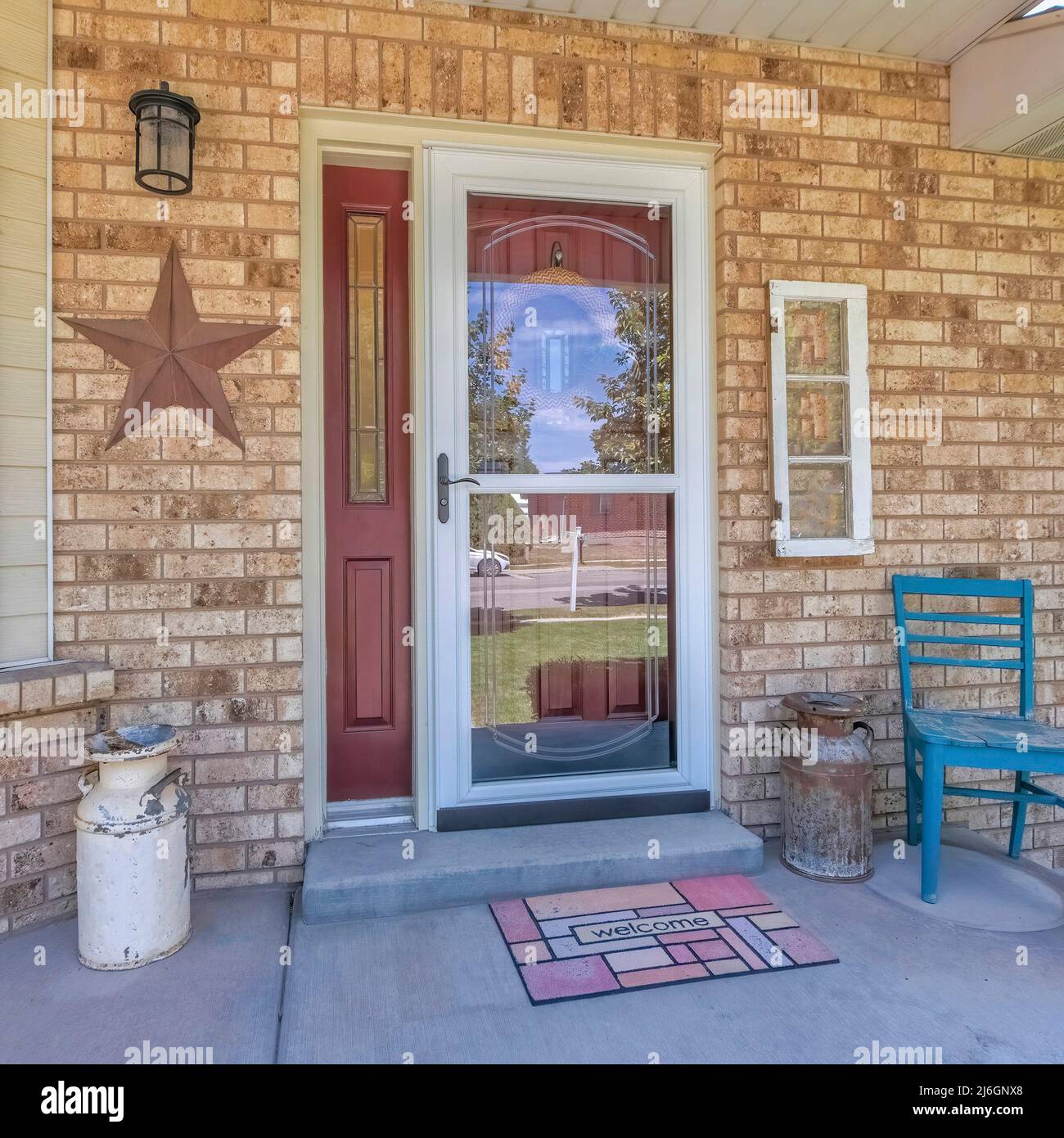 Square Home entrance with glass storm door over the burgundy door with side panel Stock Photo