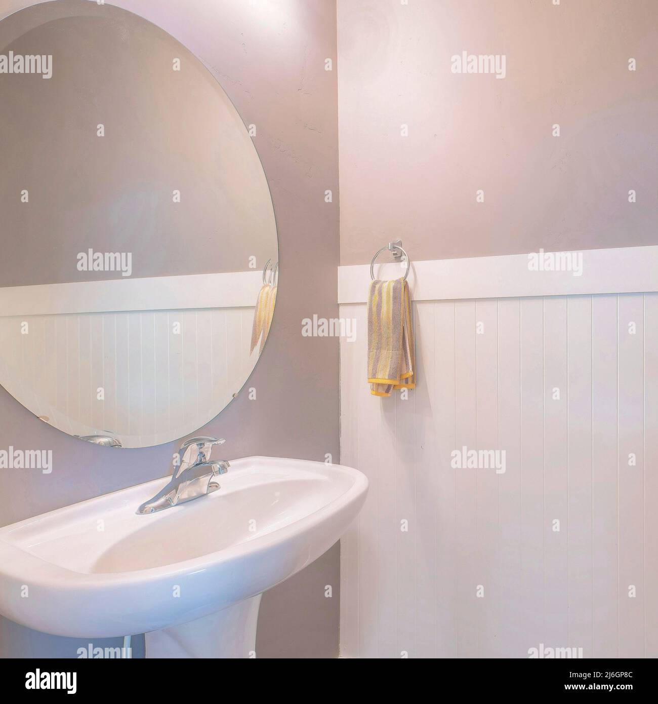 Square Pedestal sink with hanging towel on side and an oval mirror in a