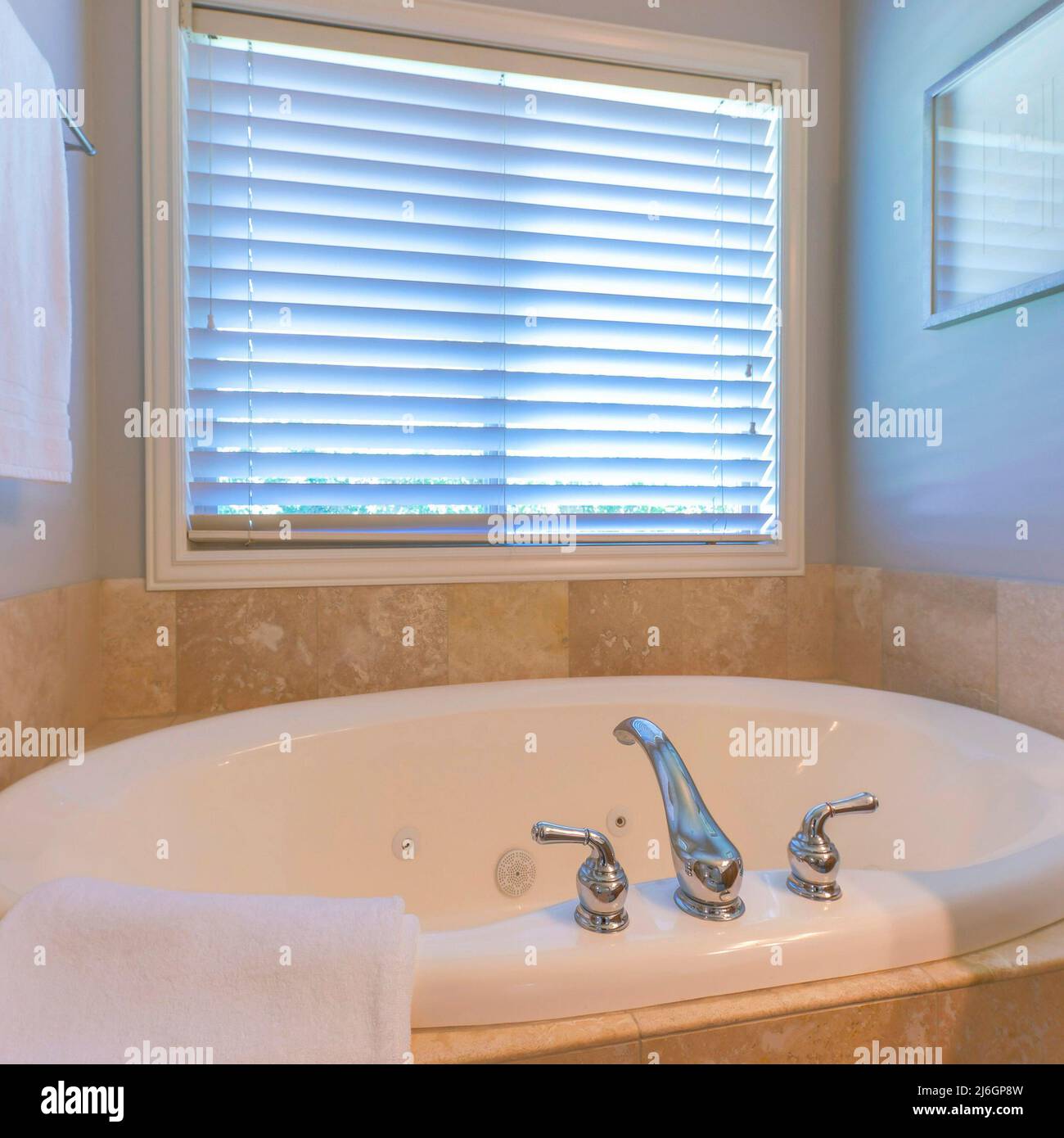 Square Alcove bathtub with tiles surround near the window with blinds