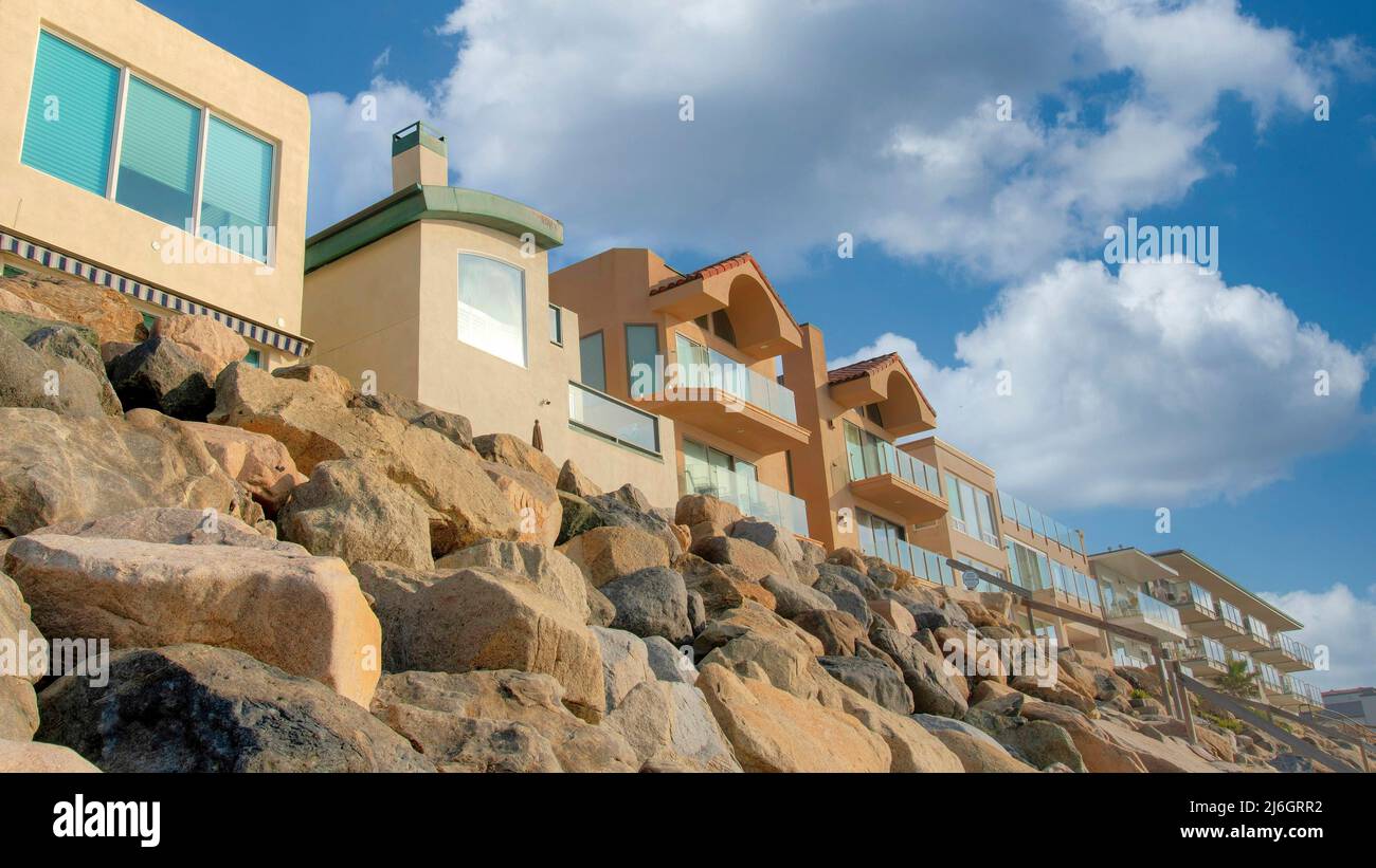 Panorama White puffy clouds Beachfront homes with large rocks seawall ...