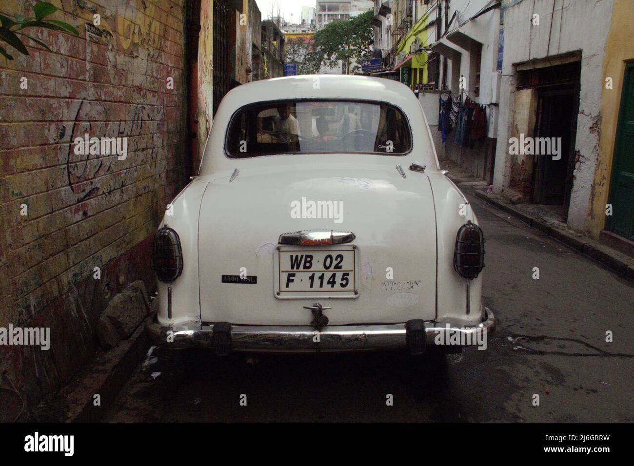 A white car (Hindustan Ambassador) is parked on an alley in Kolkata, West Bengal, India. Stock Photo