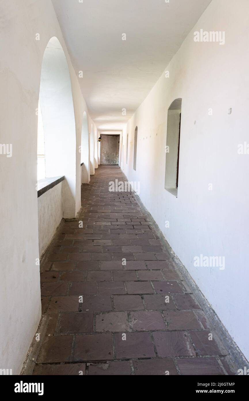 A narrow balcony corridor lined with white walls Stock Photo