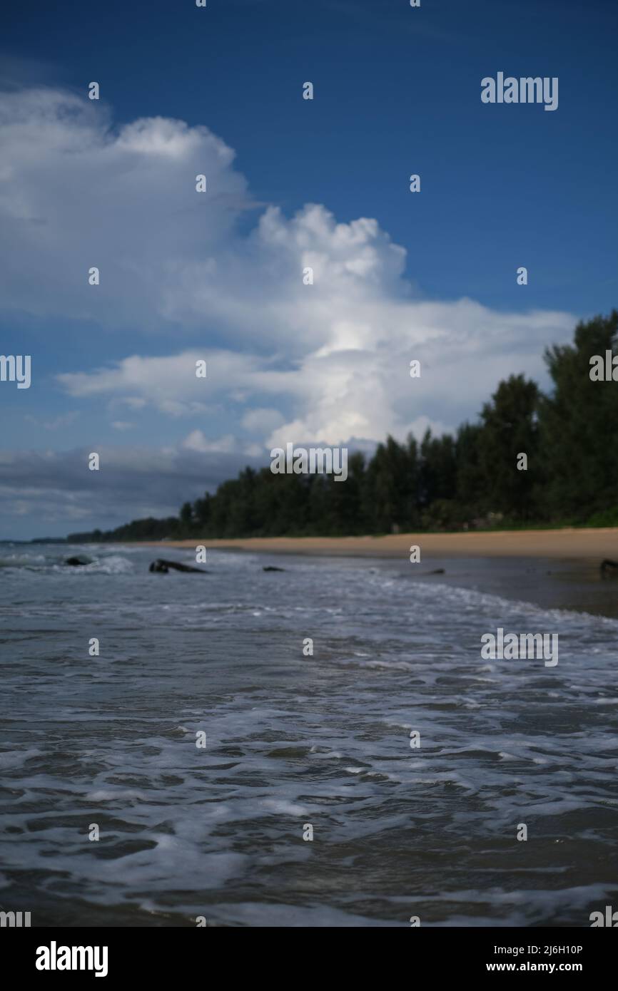 Calm water of Andaman sea near shore is reflecting a distant storm cloud Stock Photo