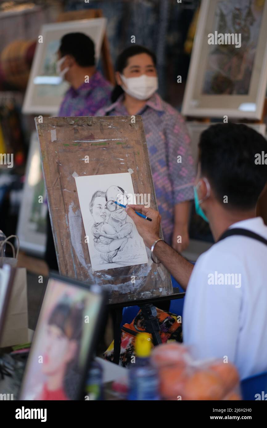 Pattaya, Chonburi  Thailand - November 26 2021: Street artist is drawing a funny cartoon for a customer couple Stock Photo