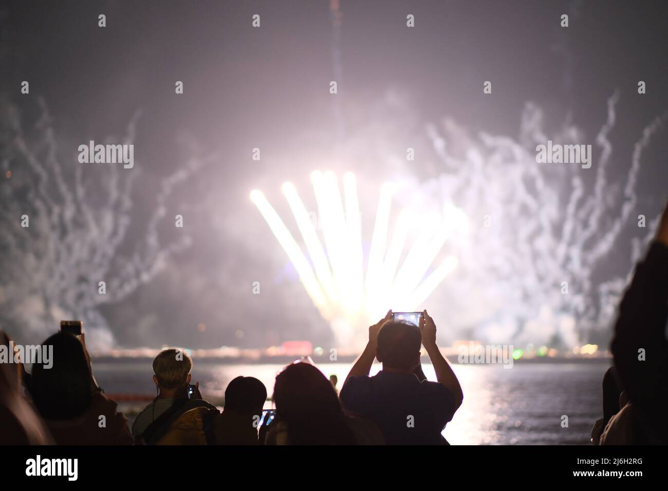 A random person from the crowd is recording fireworks with his/her smartphone Stock Photo