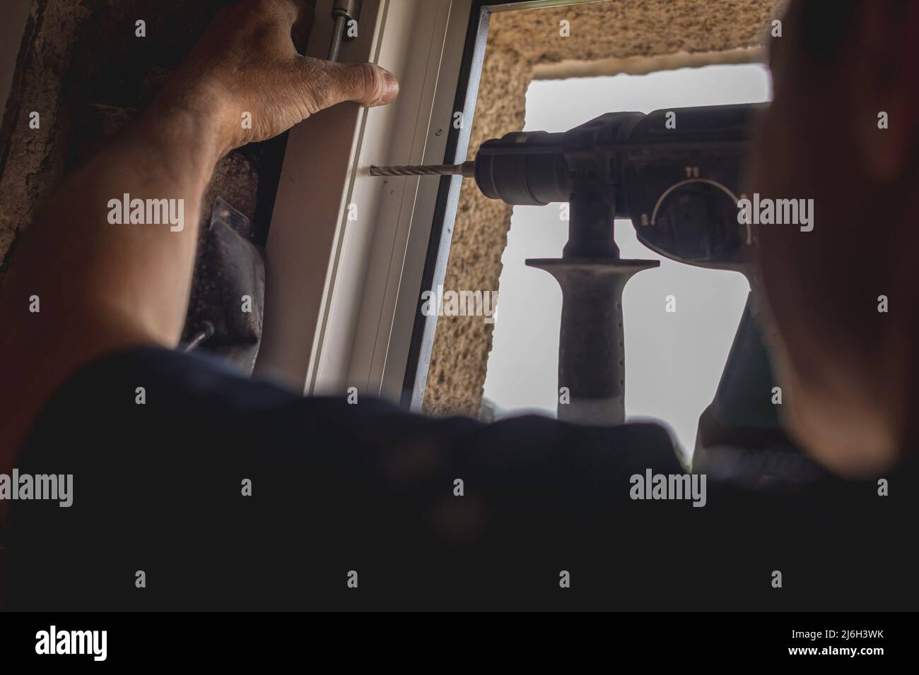 Person using a battery powered drill to install modern pvc windows or frames into an old house