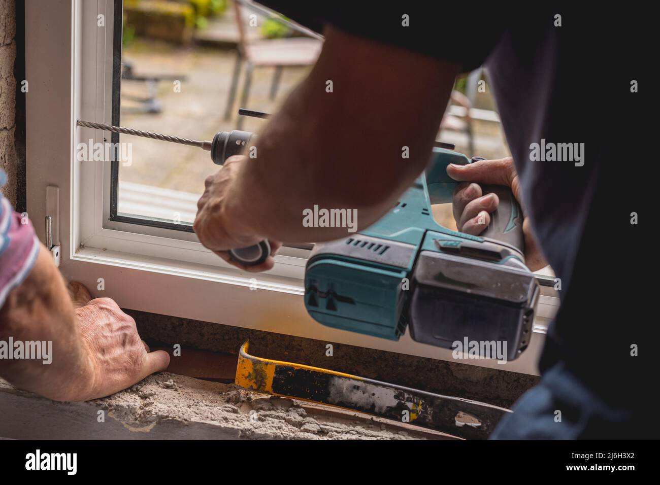 Person using a battery powered drill to install modern pvc windows or