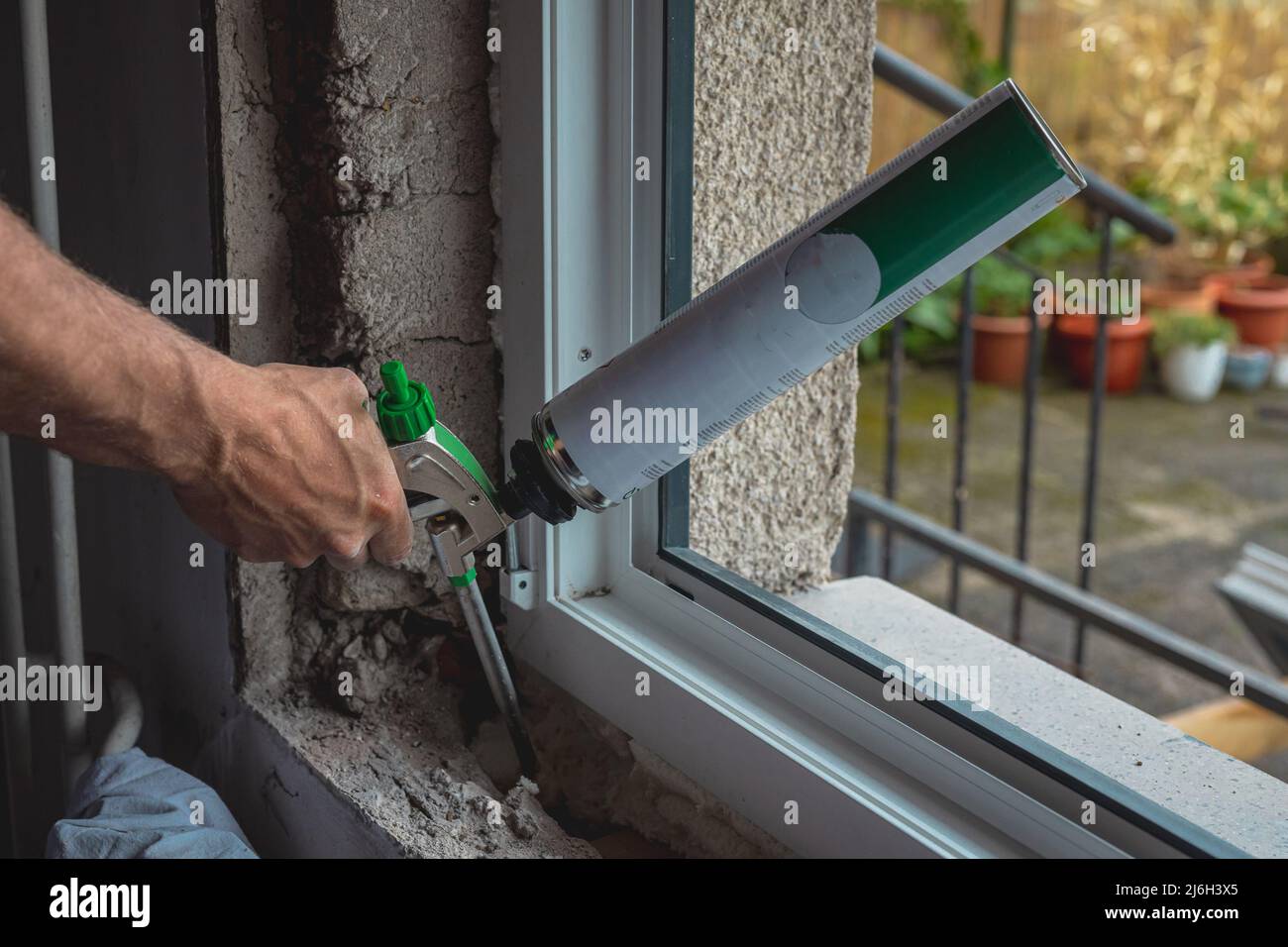 Person operating expandable foam gun while installing new windows onto