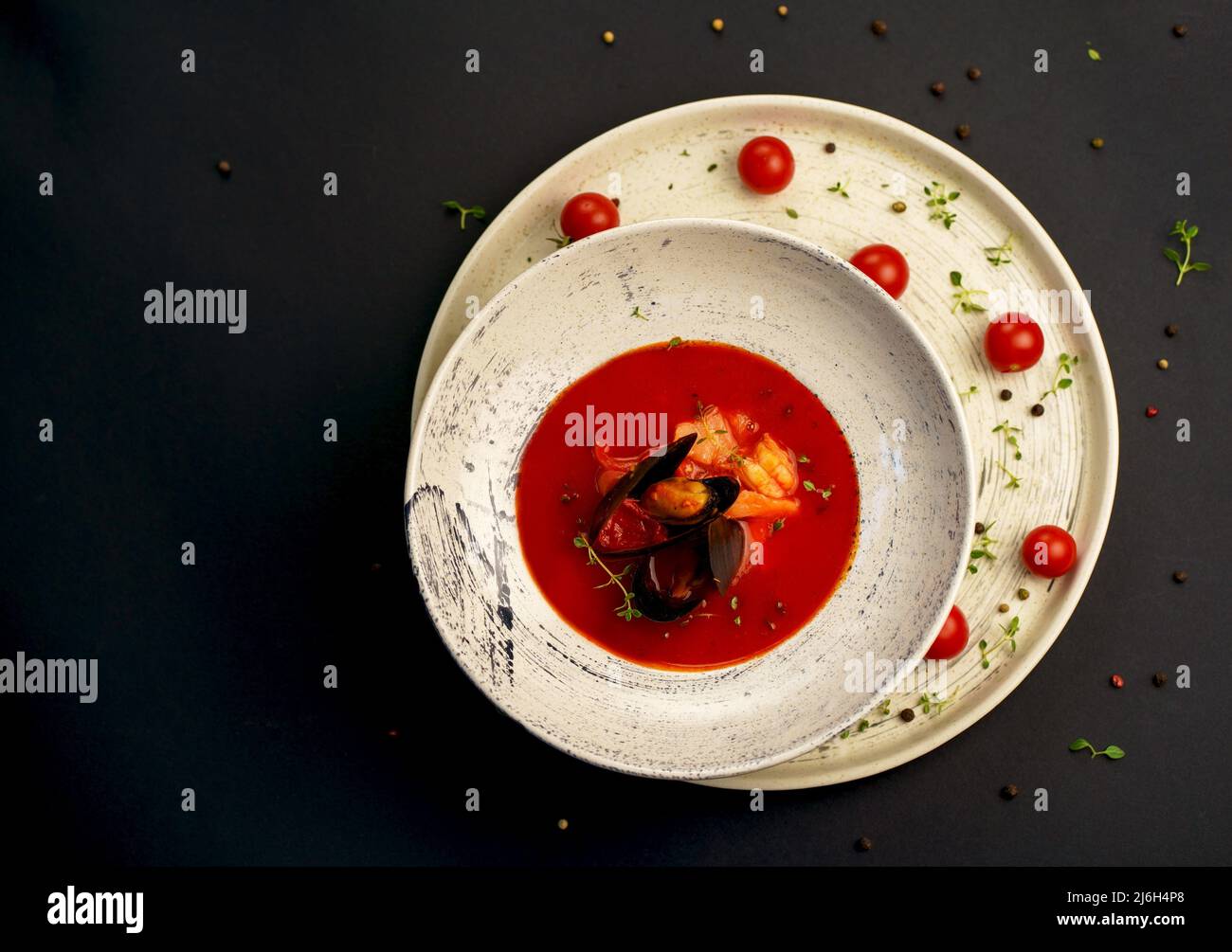 norman fish soup bouillabaisse with seafood in a plate on a black background Stock Photo