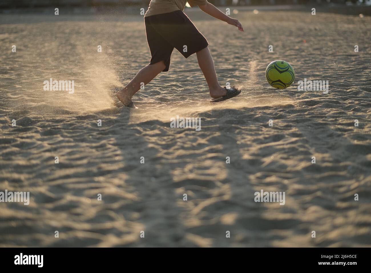 Playing football on the beach, with sand illuminated by sun Stock Photo