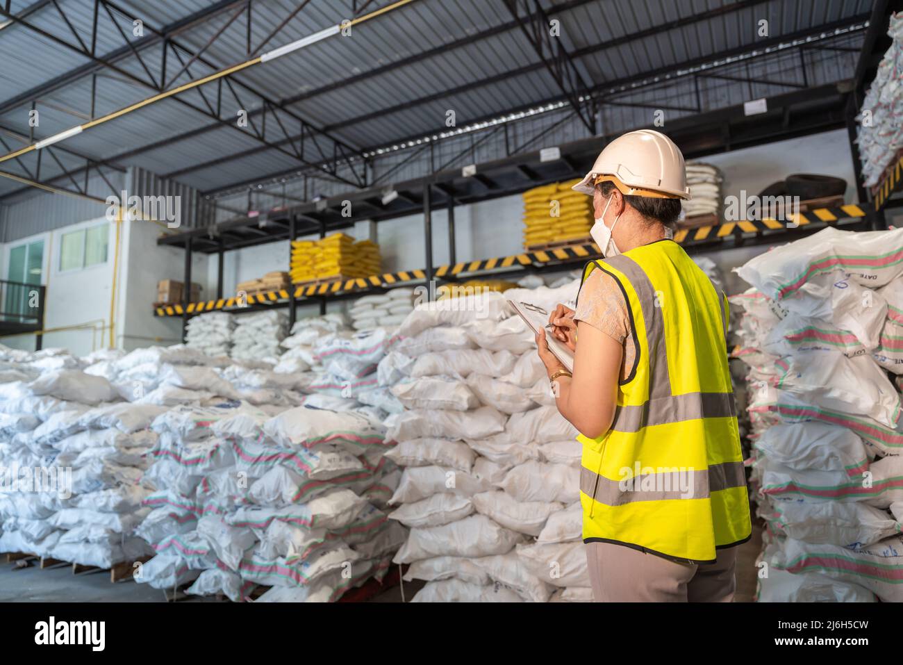 A Female warehouse worker is taking note of the number of chemicals in