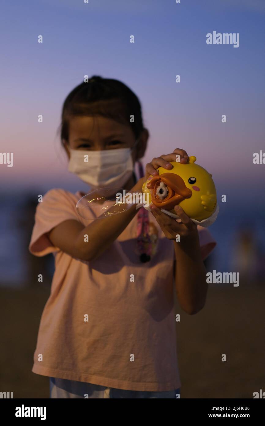 Pattaya, Chonburi  Thailand - December 11 2021: Asian girl laughs while using an automatic soap bubbles gun Stock Photo