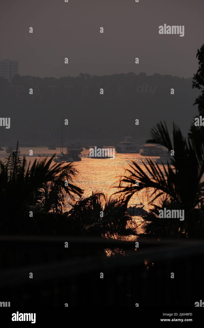 Remote view of bay of Pattaya city, Thailand, brightly lit with setting sun Stock Photo