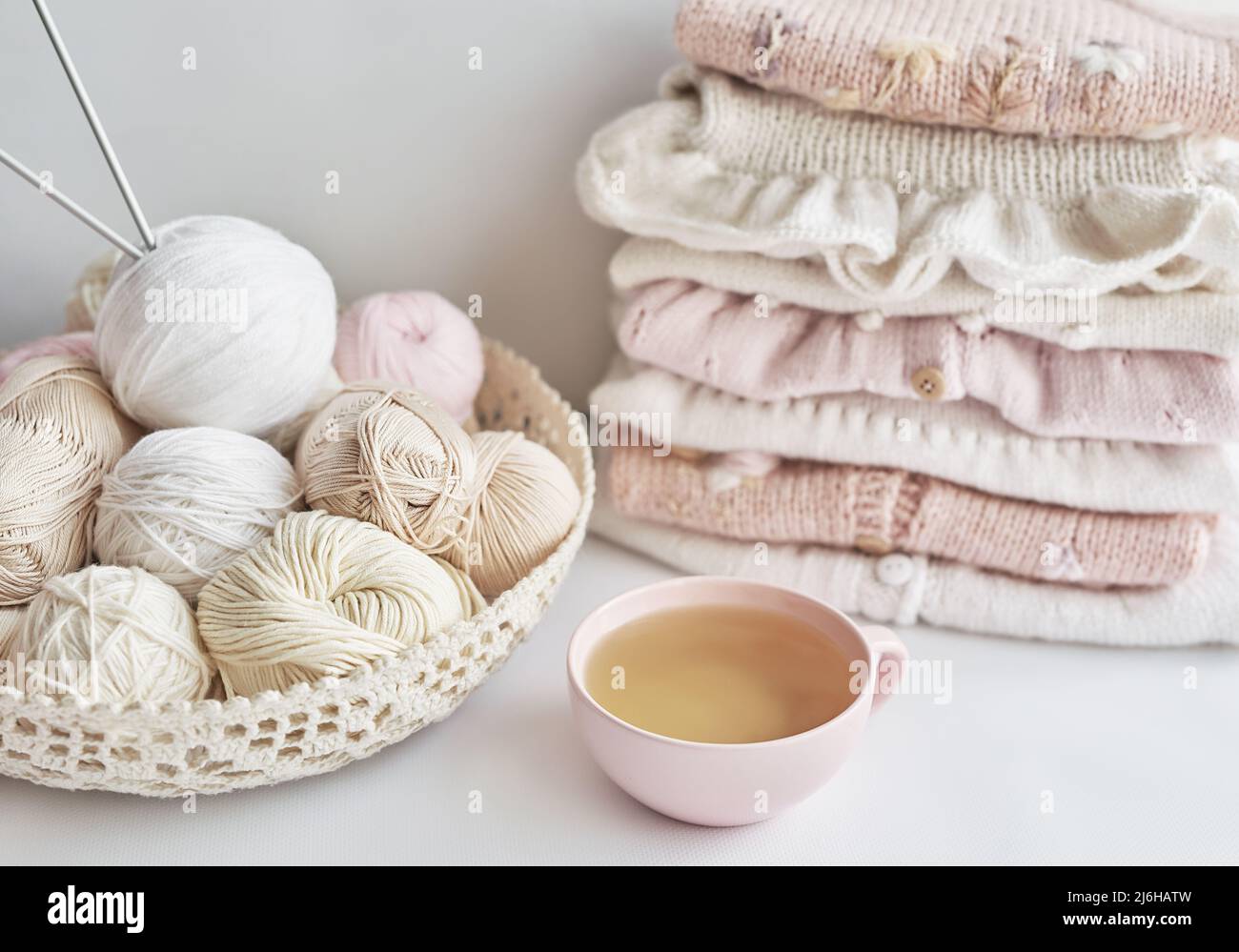 Stack of knitted clothes and balls of yarn, knitting needles ...