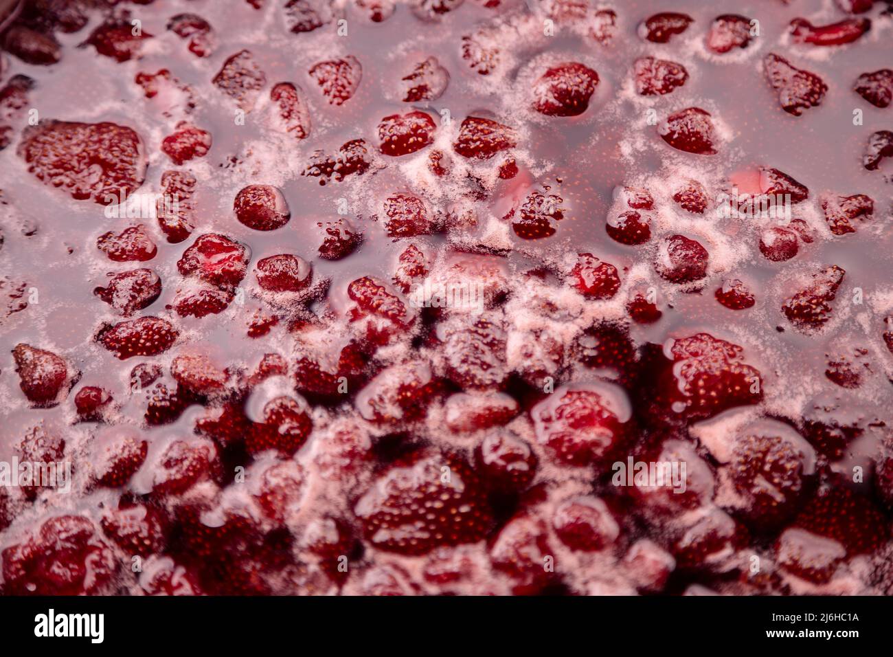 Close-up of strawberry jelly boiling in a saucepan. Preparation of strawberry jelly, marmalade or strawberry sauce. Make a strawberry jam. Boil strawberries in the pan. Soft focus, Close Up Stock Photo