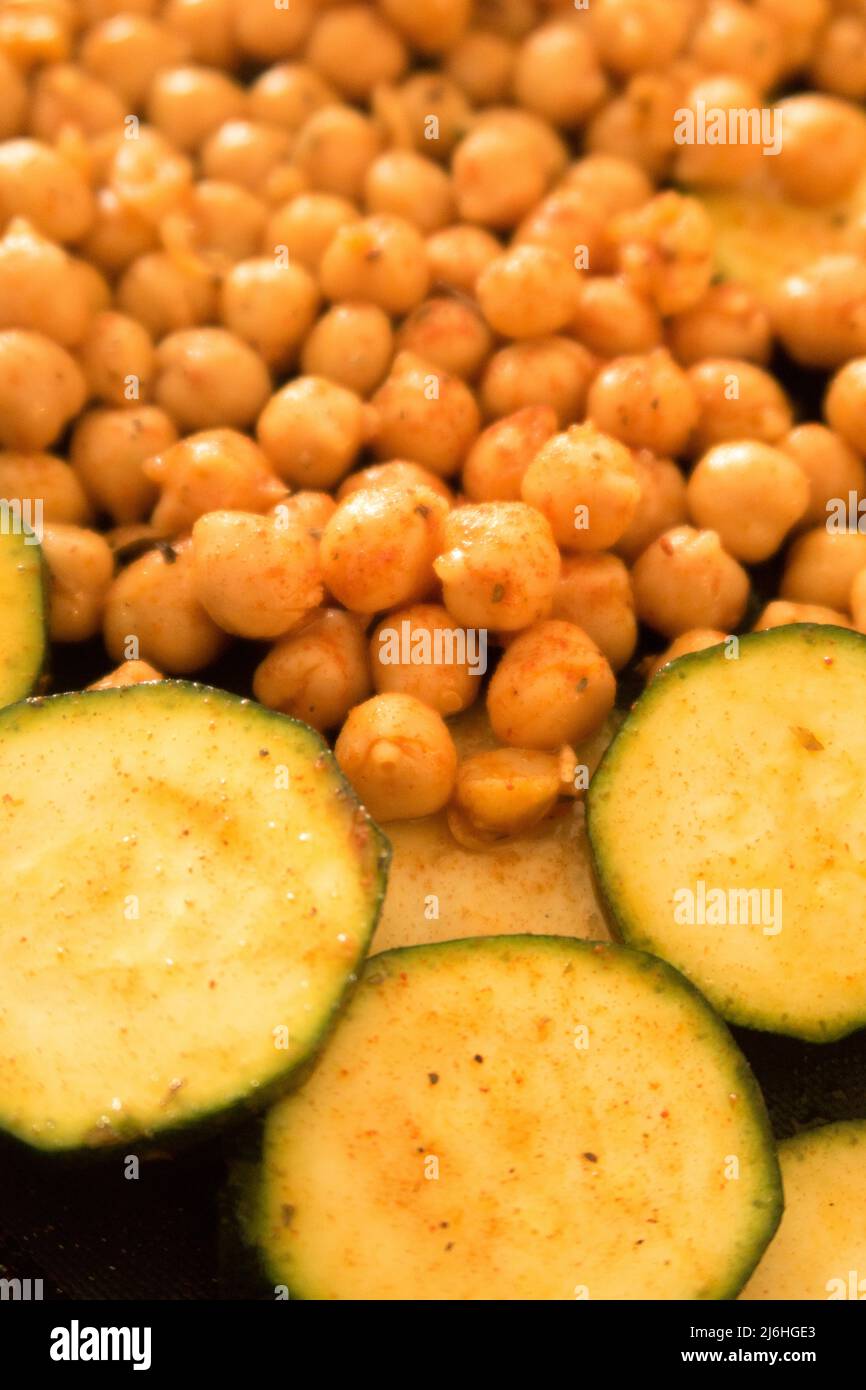 Spiced chickpeas and sliced courgette on a baking tray ready to be put in the oven Stock Photo