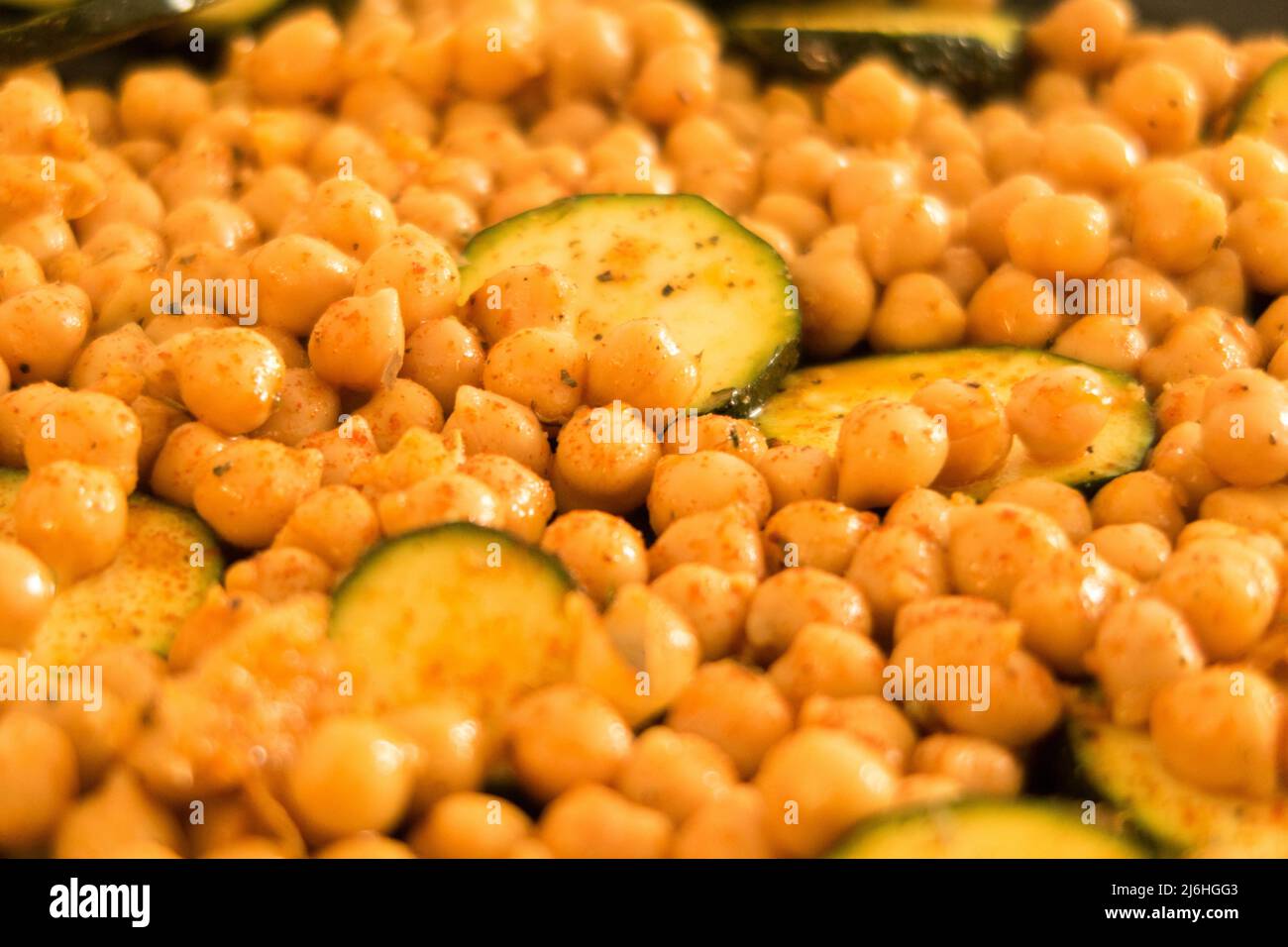 Spiced chickpeas and sliced courgette on a baking tray ready to be put in the oven Stock Photo