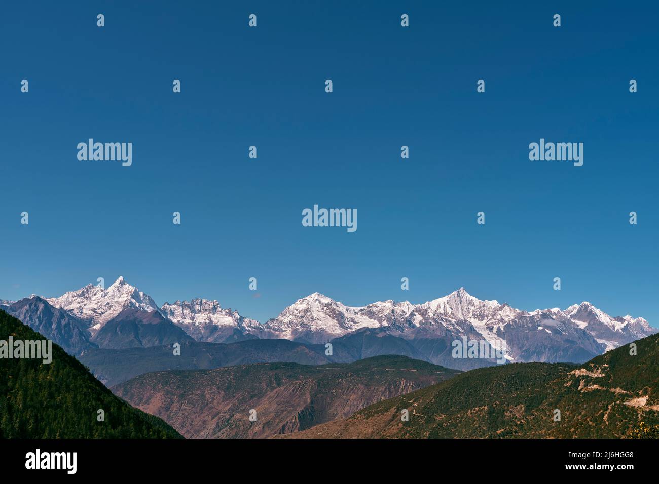 snow capped meili mountain range under blue sky in china's sichuan province Stock Photo