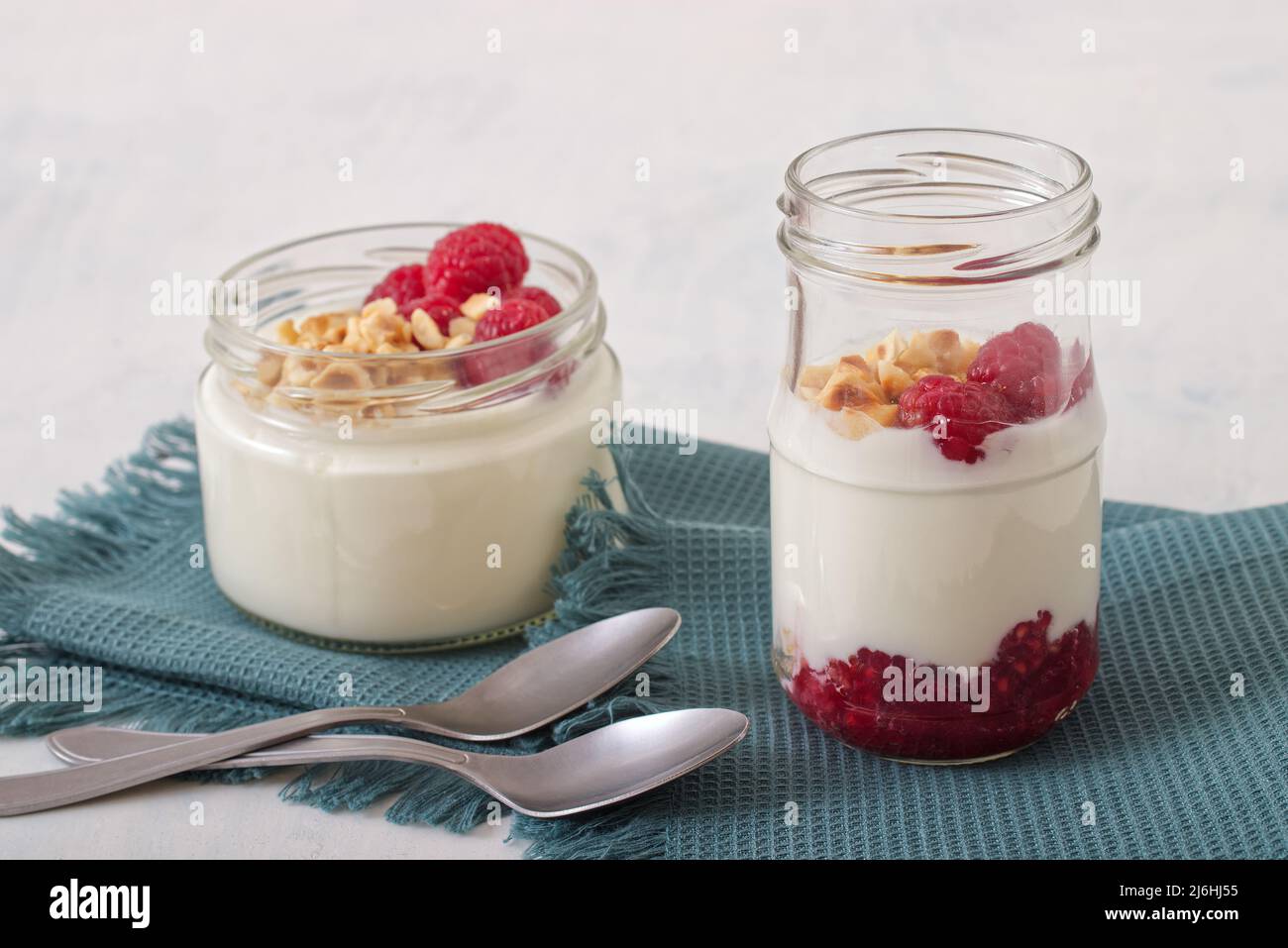Healthy nutrition food, plain Greek yogurt, fresh raspberries and crushed hazelnuts on white
