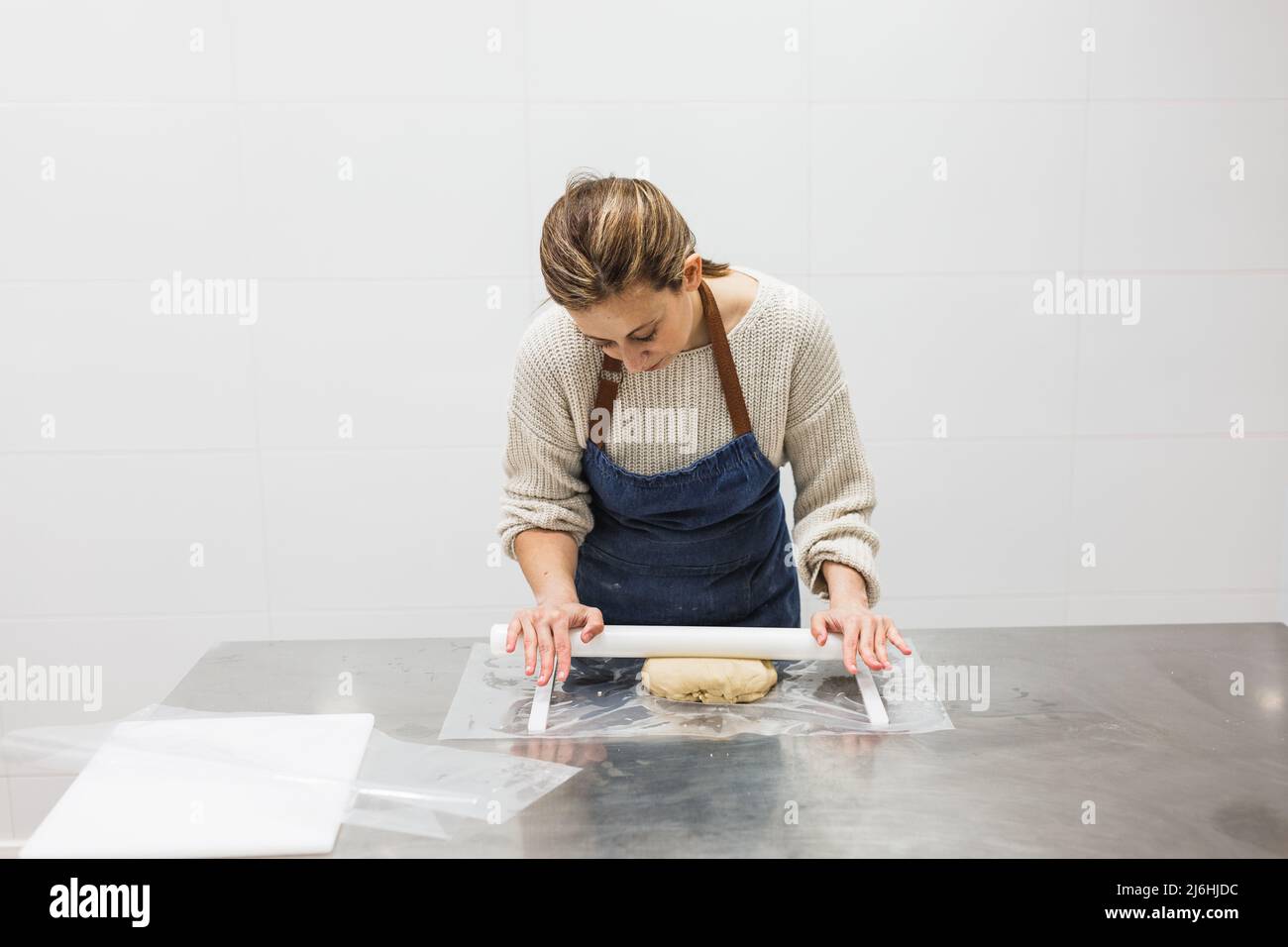 Cook stretching dough with rolling pin in pastry kitchen Stock Photo