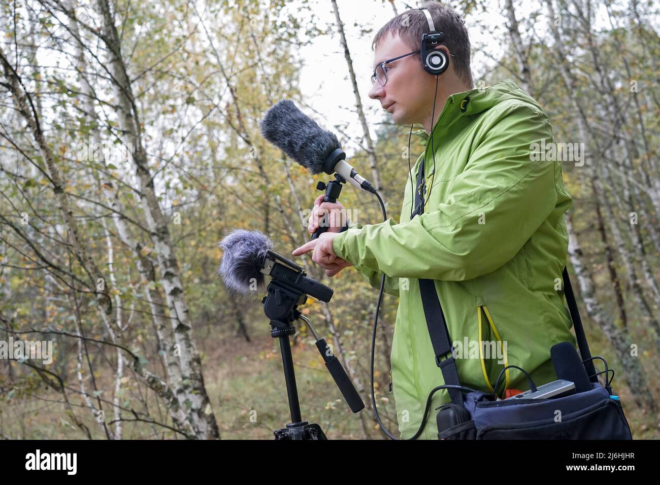The guy with Shotgun Condenser Microphone and headphones is recording the sounds of nature. Recording Ambient Sounds Stock Photo