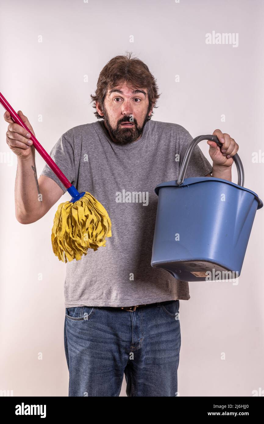 Middle-aged, recently divorced man with a mop and bucket. He doesn't know how to do housework. Newbie. Concept of man in distress. Stock Photo