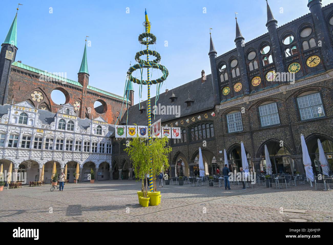 Lubeck, Germany, May 1, 2022: Market place at the historic town hall and maypole decorated with fluttering ribbons in blue yellow like the flag of Ukr Stock Photo