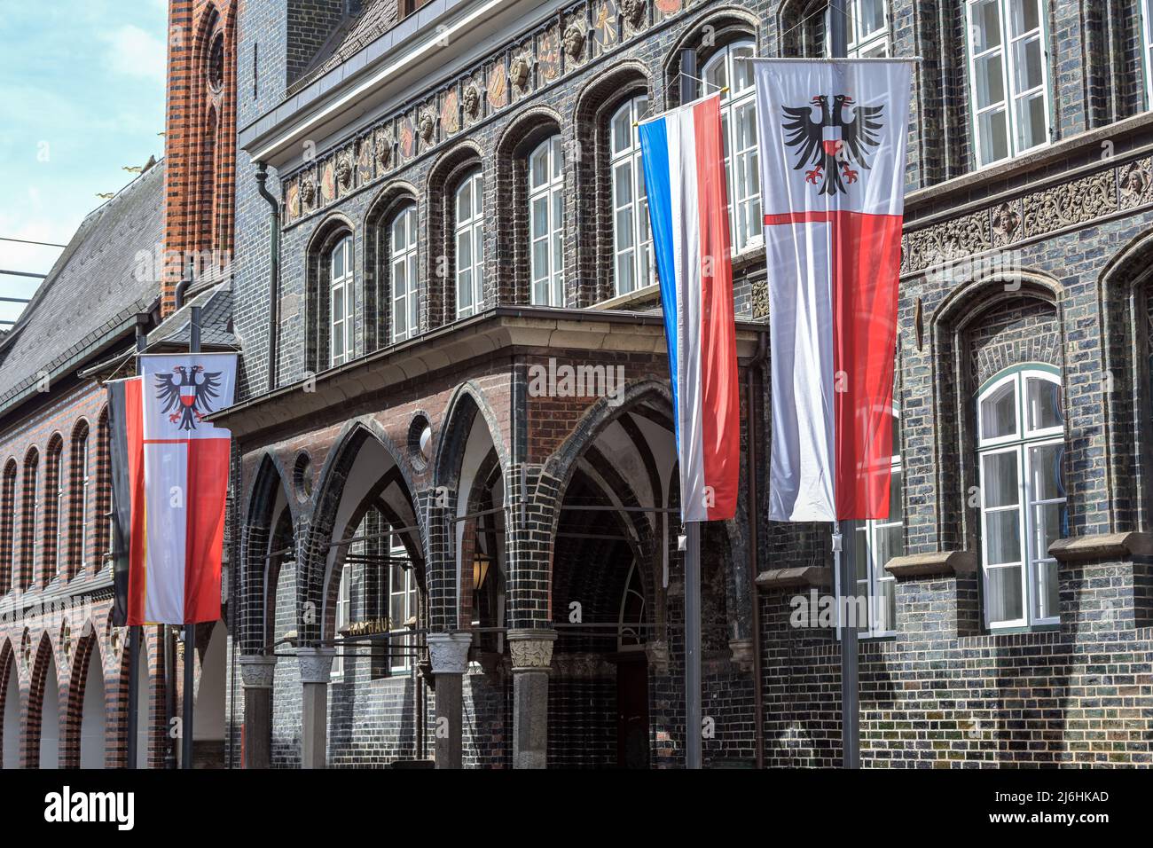 Entrance at the historical town hall of Lubeck with the flag of the hanseatic city showing a double headed eagle and the Schleswig-Holstein flag with Stock Photo