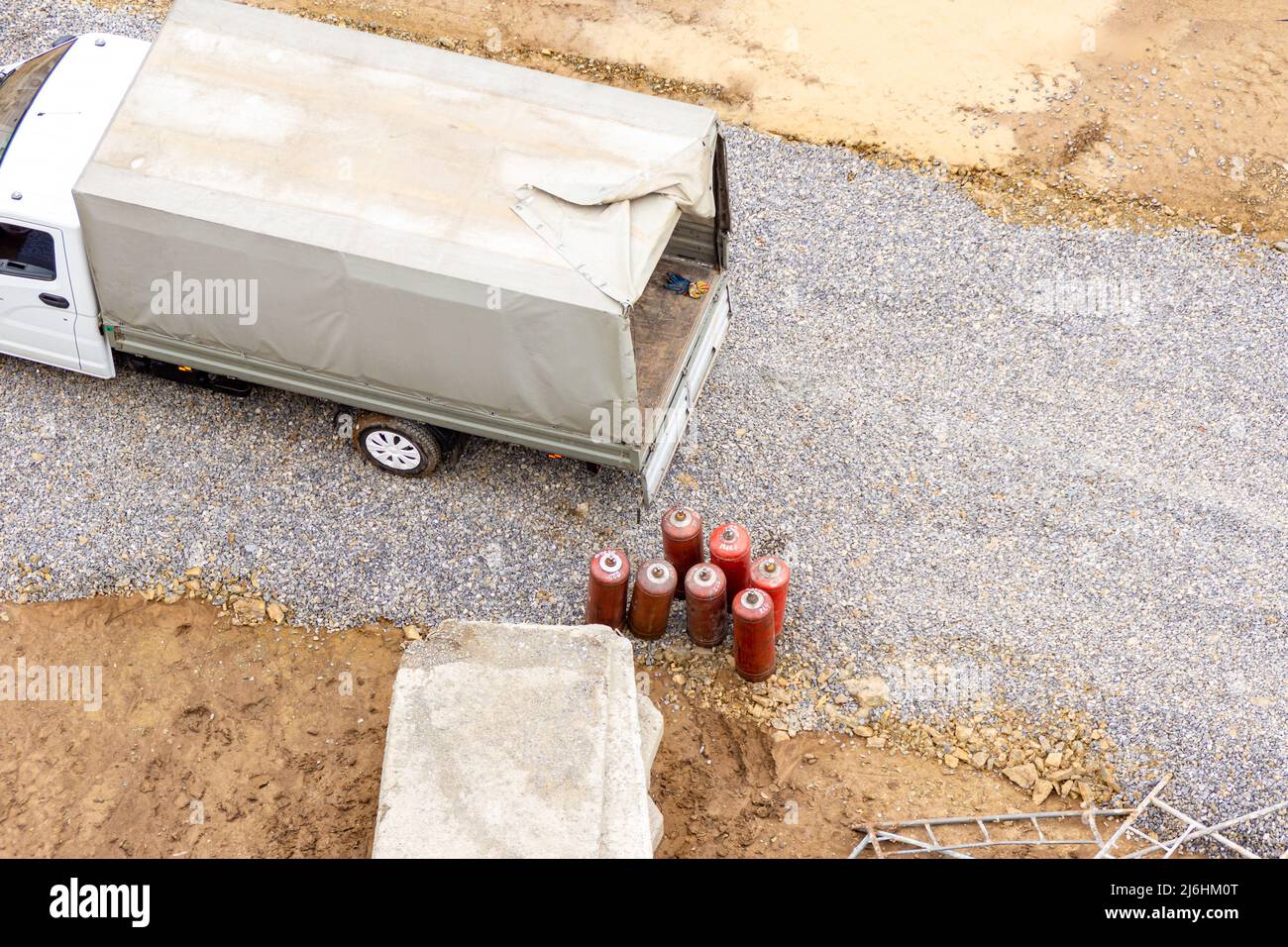 A small truck with an awning on the body stands on a construction site near several red gas cylinders - propane, selective focus Stock Photo