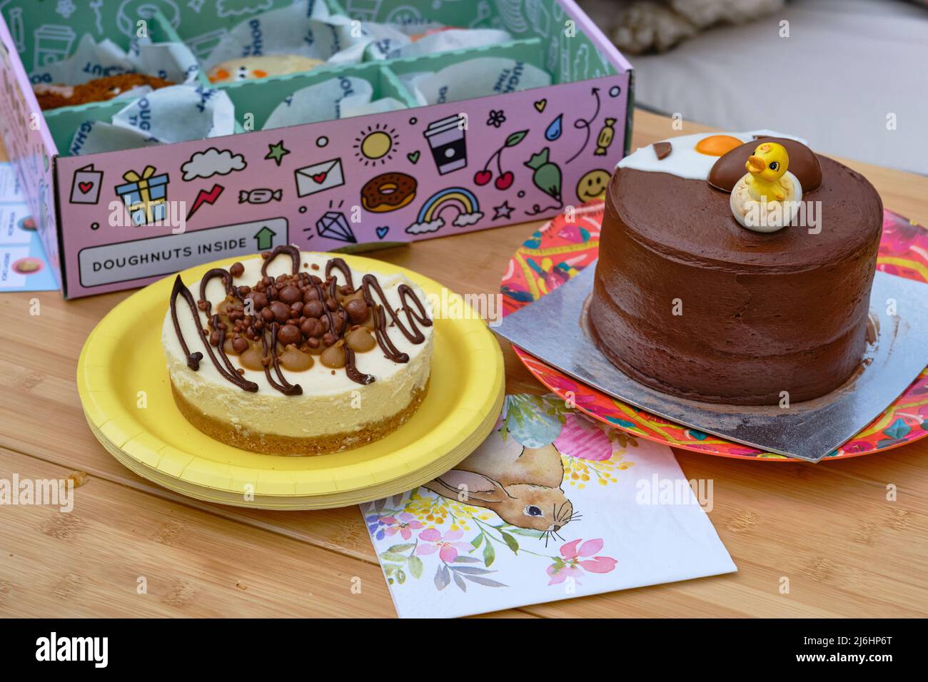 An Easter chocolate cake, cheesecake and doughnuts presented on an outdoor table Stock Photo