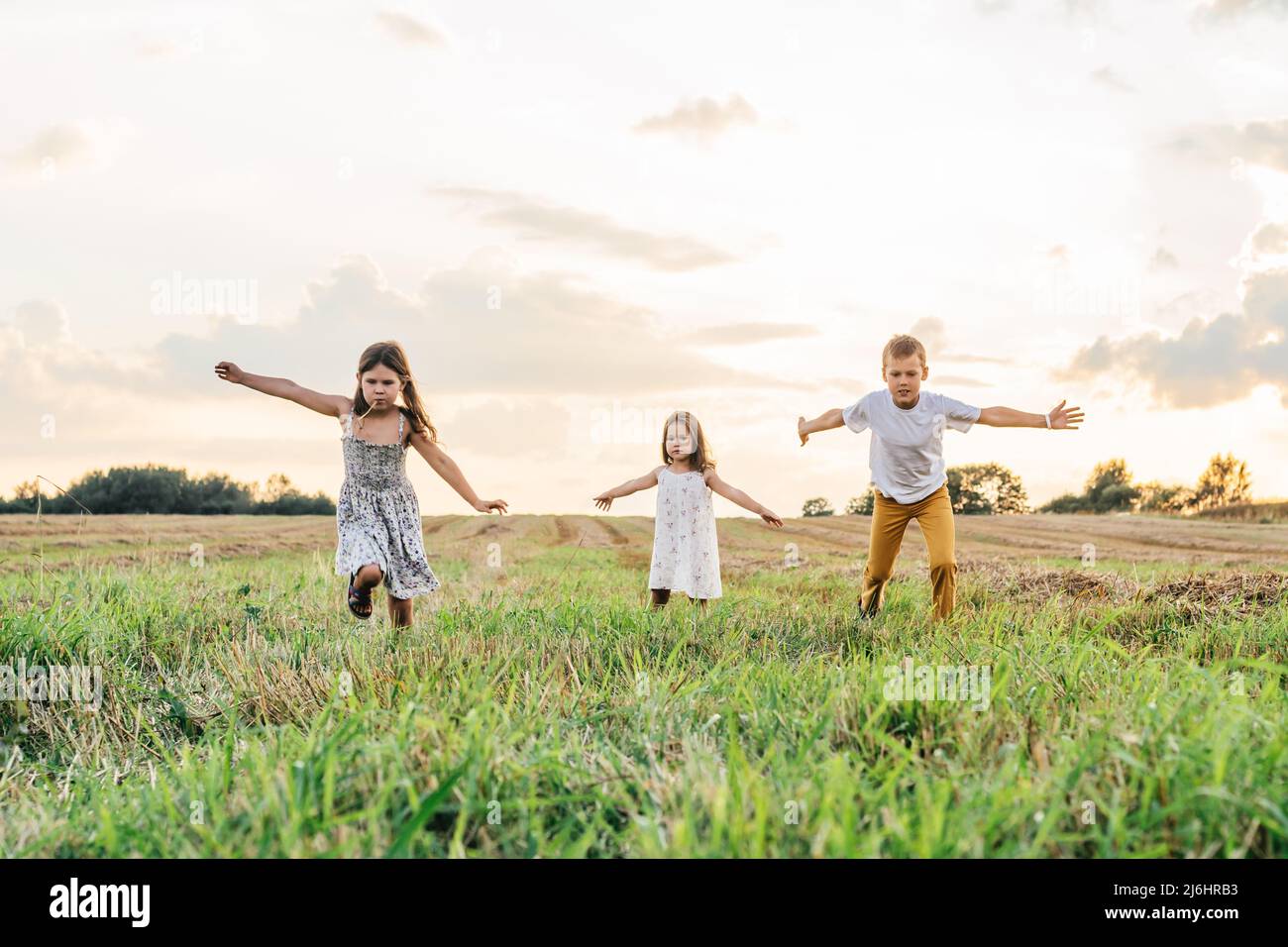Portrait of three children playing game of catch, jumping and running