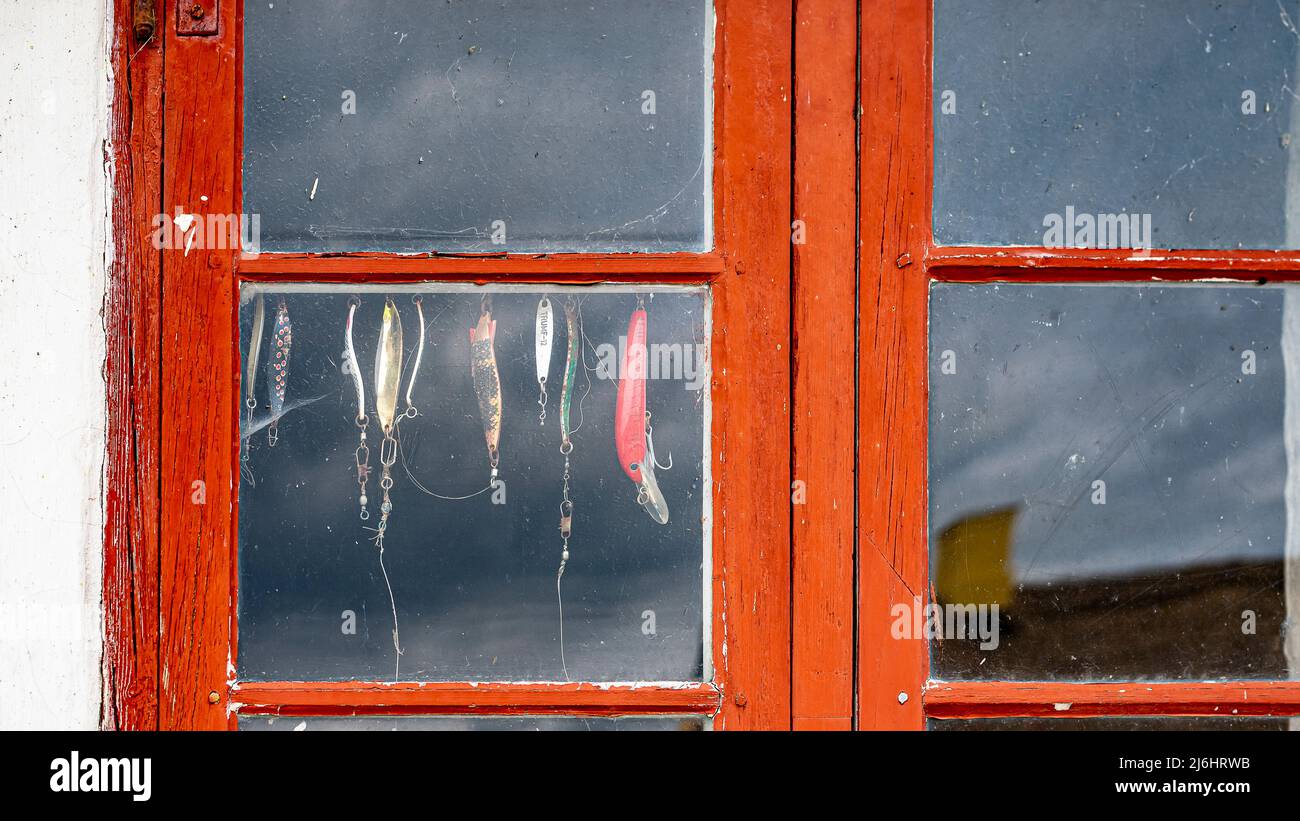 spinning lures hanging in a red window on an old fishing hut, Jyllinge, Denmark, May 1, 2022 Stock Photo