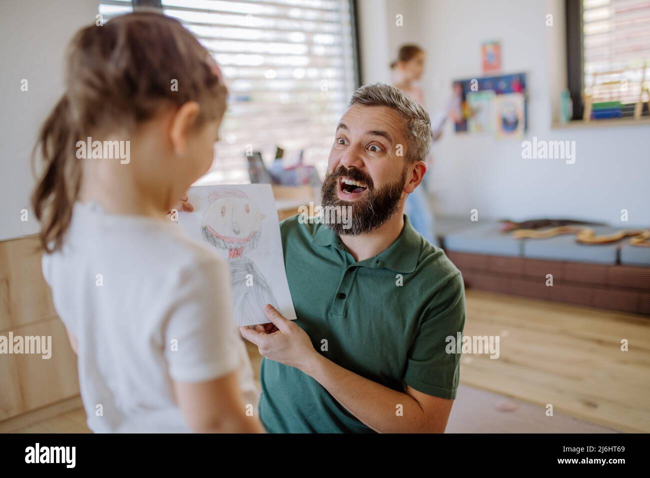 Happy father getting drawings from his little daughter at home. Stock Photo