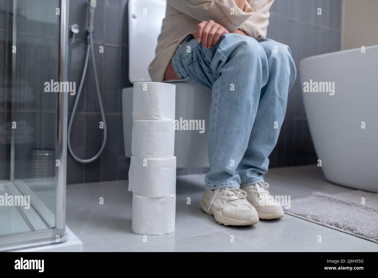 A young woman sitting on a toilet bowl Stock Photo