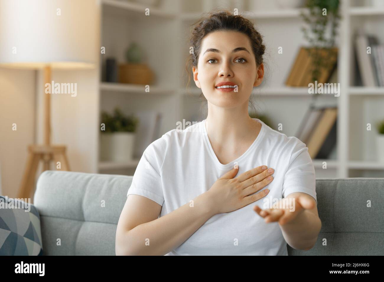 Delighted charming woman with gapped teeth in cozy outfit holding palms on  chest in grateful or thankful pose smiling broadly receiving warm Stock  Photo - Alamy