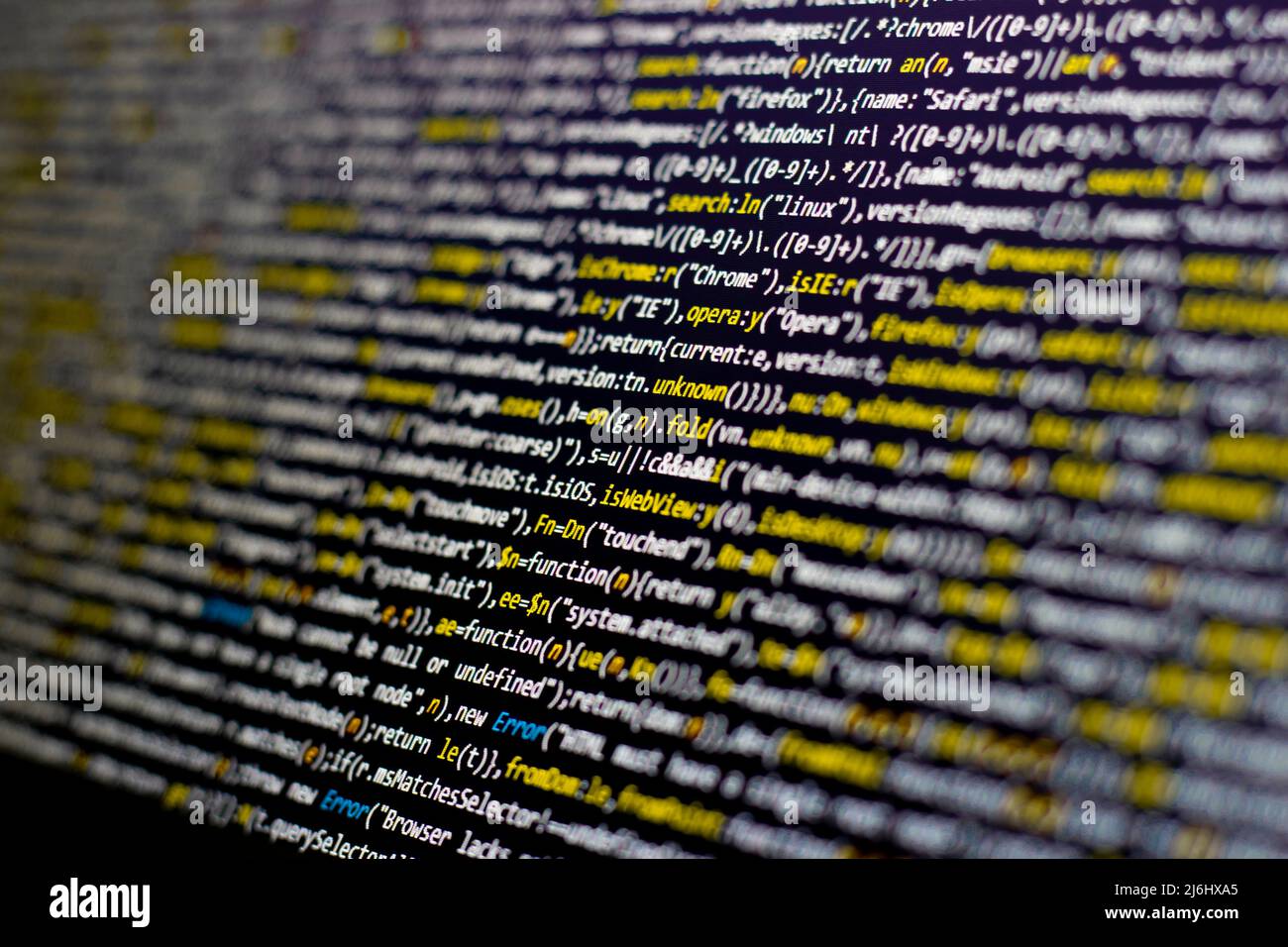 yellow code lines selective focus on the black screen background. blurred white letters side view. Stock Photo