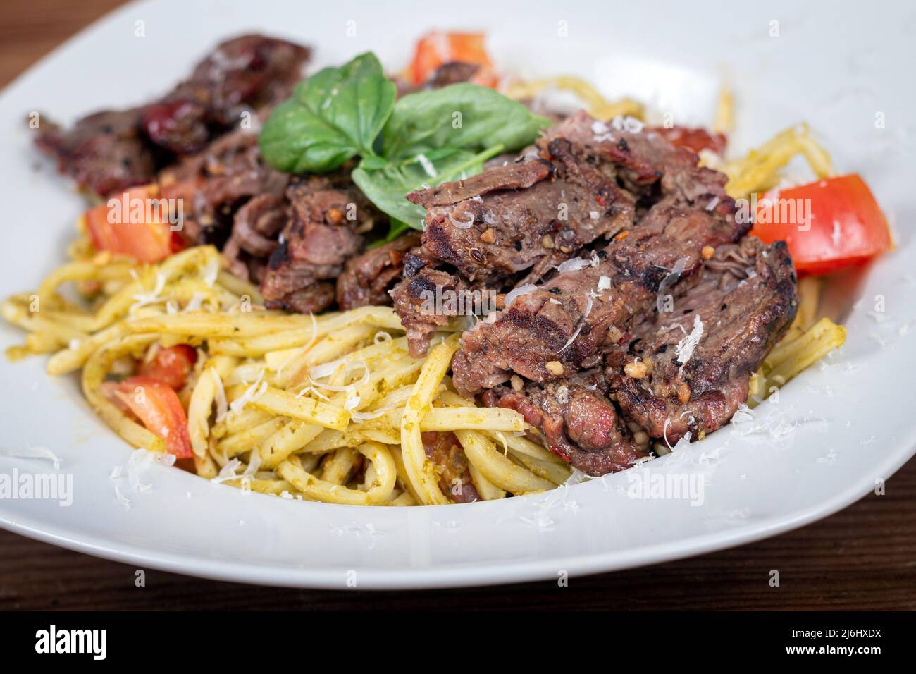 Grilled flank steak over basil pesto and tomato keto pasta dish Stock