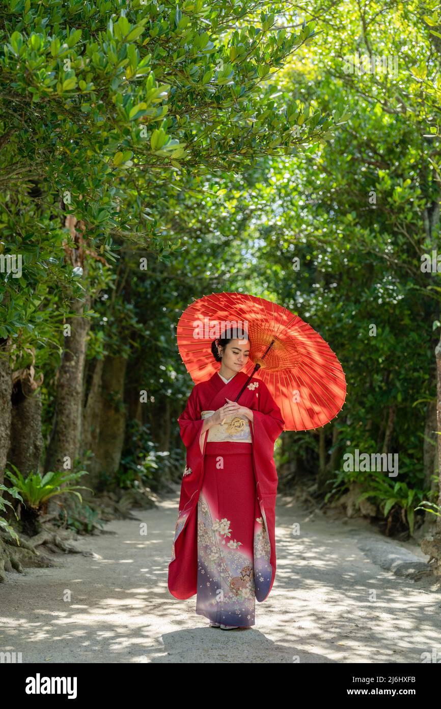 Young woman wearing kimono in the fukugi tree lanes of Bise Village