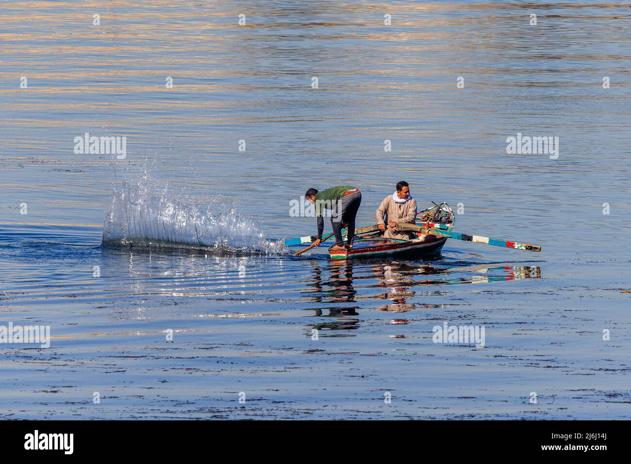 traditional fishing on the river nile in egypt by striking the water with a long pole to drive fish into nets from a low rowing boat Stock Photo