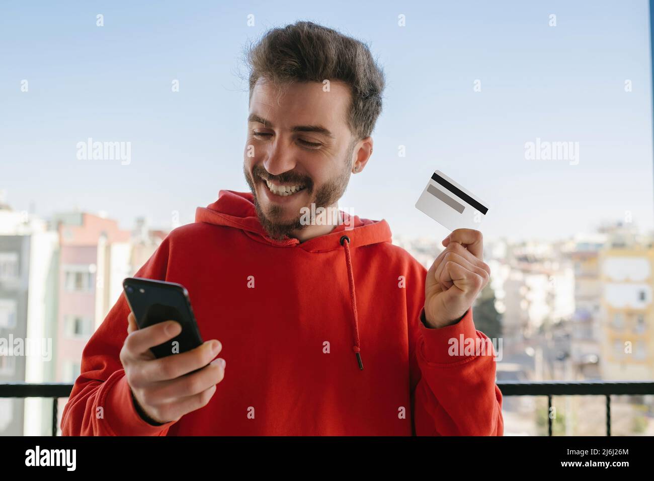 Internet shopping, young man is experiencing happiness after secure online shopping, he waves his credit card and smiles, facial expression and enjoym Stock Photo
