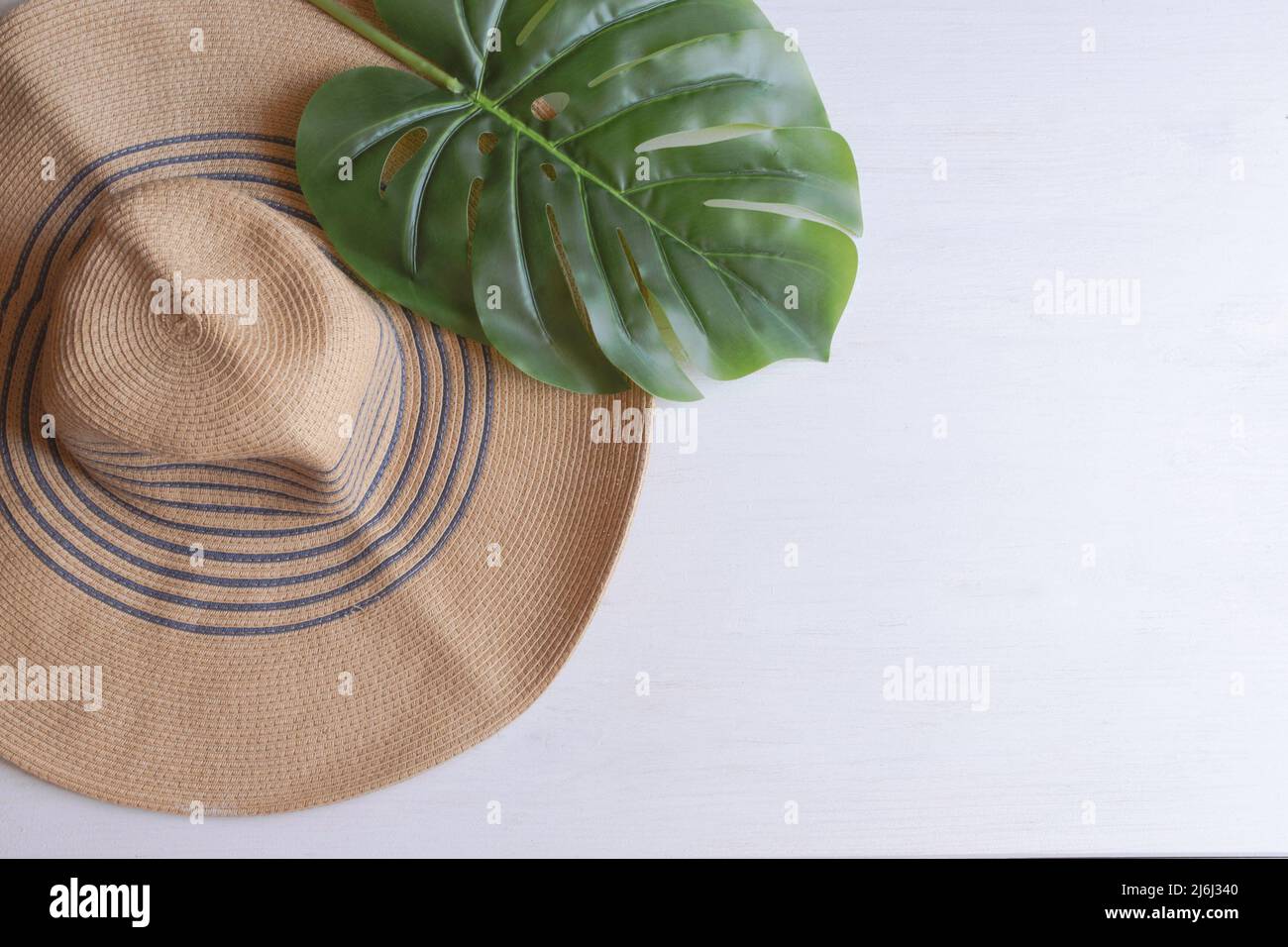 Big straw hat with palm leaf on white wooden background. Summer ...