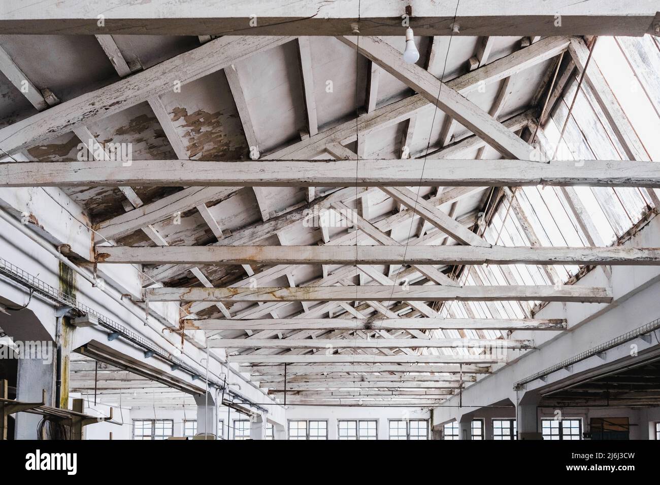 Interior of a wooden roof with white beams in a spacious factory. Stock Photo